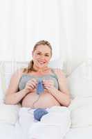 Adorable pregnant woman knitting on her bed