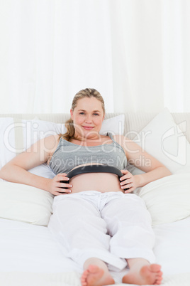 Pregnant woman putting her earphones on her belly