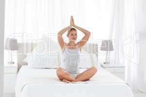 Beautiful woman practicing yoga on her bed