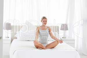 Beautiful woman practicing yoga on her bed