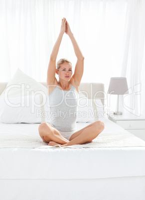 Beautiful woman practicing yoga on her bed