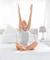 Beautiful woman practicing yoga on her bed