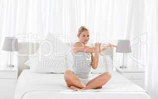 Beautiful woman practicing yoga on her bed