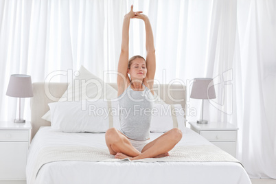 Beautiful woman practicing yoga on her bed