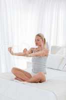 Beautiful woman practicing yoga on her bed