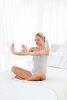 Beautiful woman practicing yoga on her bed