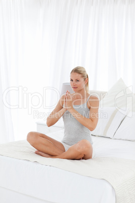 Beautiful woman practicing yoga on her bed