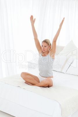 Beautiful woman practicing yoga on her bed