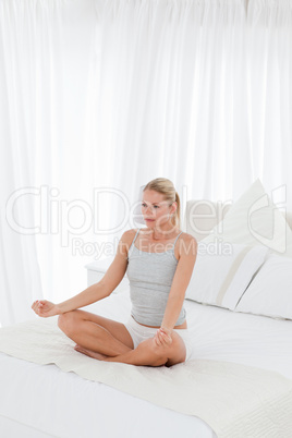 Beautiful woman practicing yoga on her bed