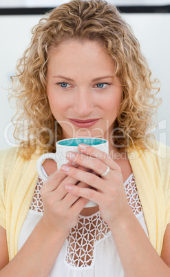 Pretty woman drinking coffe in her kitchen at home