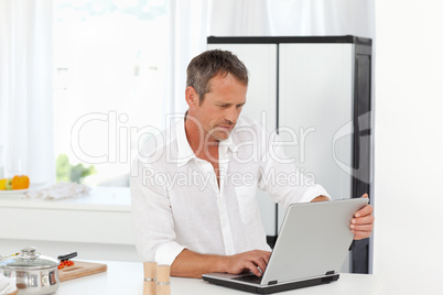 Man working on his laptop in his kitchen