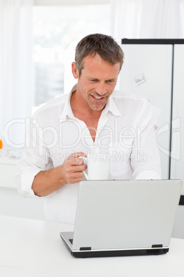 Man looking at his laptop while he is drinking