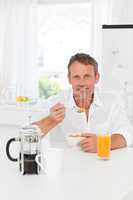 Handsome man having his breakfast in the kitchen