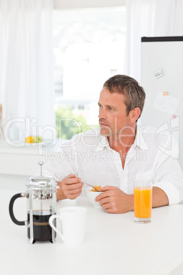 Handsome man having his breakfast in the kitchen