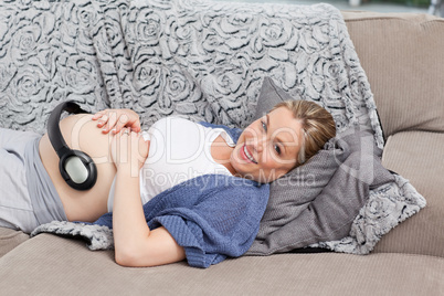 Young woman putting her earphones on her belly