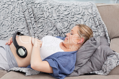Young woman putting her earphones on her belly
