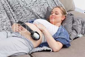 Young woman putting her earphones on her belly