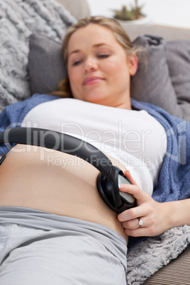 Young woman putting her earphones on her belly