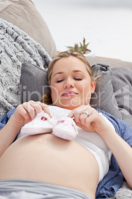 Young woman with childrens shoes on her belly