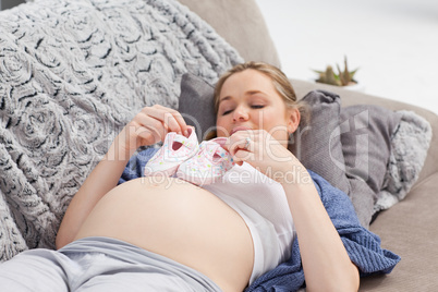 Young woman with childrens shoes on her belly