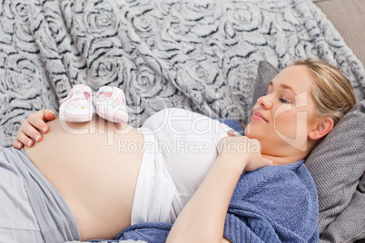 Young woman with childrens shoes on her belly