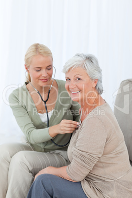 Nurse taking the heartbreat of her patient at home