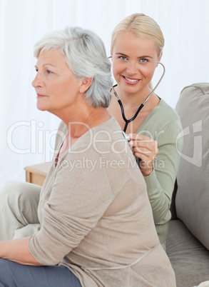 Nurse taking the heartbreat of her patient at home