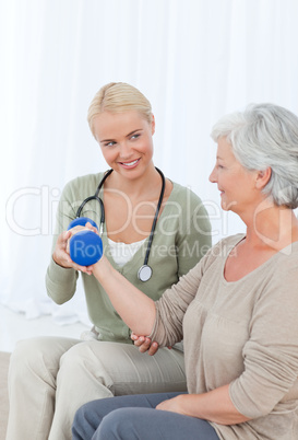 Beautiful nurse helping her patient to do exercises