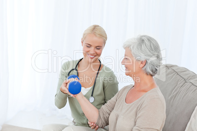 Beautiful nurse helping her patient to do exercises