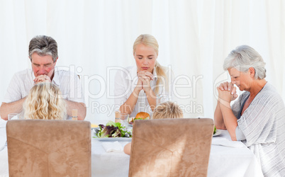 Pretty family praying at the table