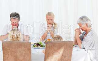 Pretty family praying at the table