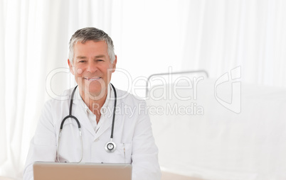 A senior doctor working on his laptop in his office