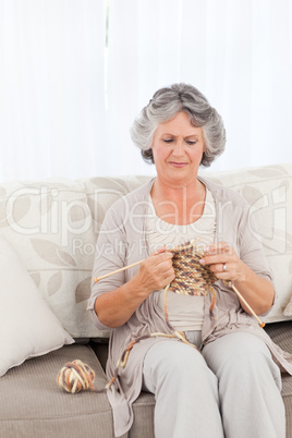 Senior woman knitting on her sofa