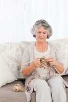 Senior woman knitting on her sofa