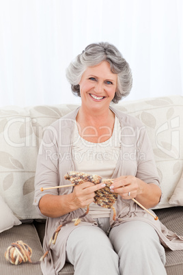 Senior woman knitting on her sofa