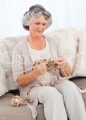 Senior woman knitting on her sofa