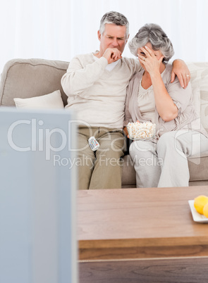 Mature couple watching tv in their living room