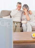 Mature couple watching tv in their living room