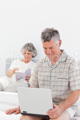 Man working on his laptop while his wife is reading