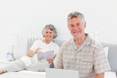 Man working on his laptop while his wife is reading Man working on his laptop while his wife is reading