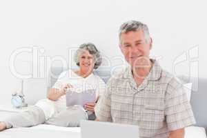 Man working on his laptop while his wife is reading