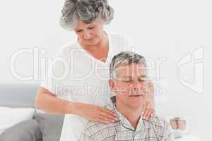 Retired woman giving a massage to her husband at home