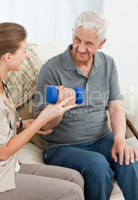 Lovely nurse helping her patient to do exercises