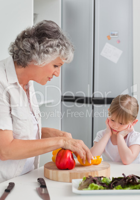 Little girl looking at her grandmother who is cooking