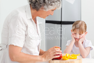 Little girl looking at her grandmother who is cooking