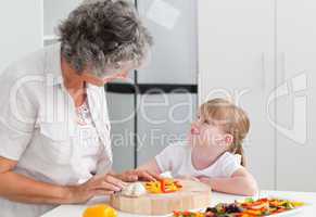 Little girl looking at her grandmother who is cooking