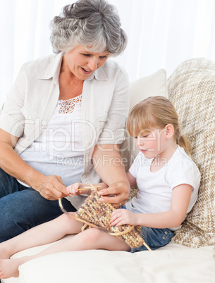 Grandmother helping her little girl to knit