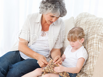 Grandmother helping her little girl to knit