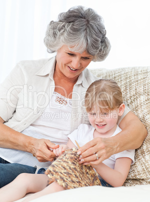 Grandmother helping her little girl to knit