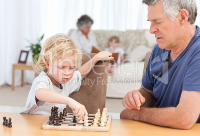 Young boy playing chess with his grandfather